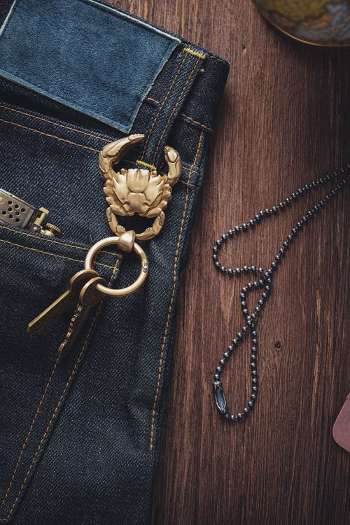 Free Top view shot of handmade crab keychain on denim with chain necklace on wooden surface. Stock Photo