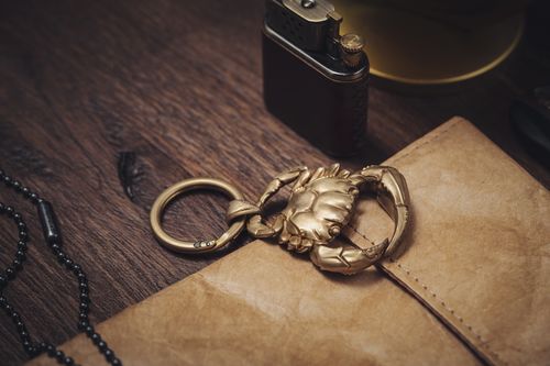 Free Close-up of a golden crab keychain set on a wooden desk with vintage items, showcasing luxury and style. Stock Photo