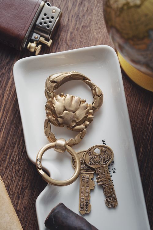 Free Golden crab-shaped keychain with vintage keys on a modern ceramic tray, offering a chic and stylish look. Stock Photo