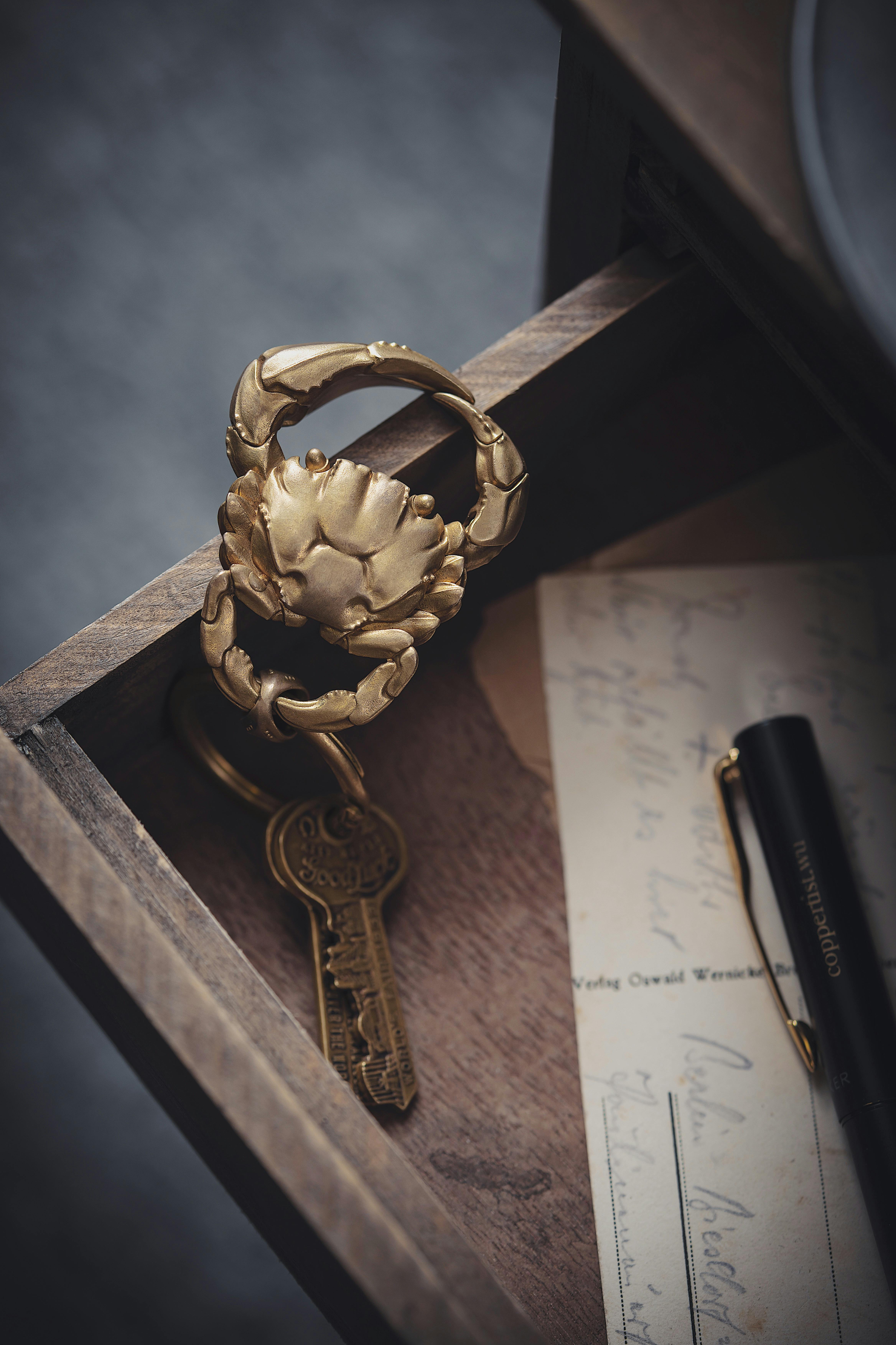 A golden crab keychain with keys inside a wooden drawer, showcasing elegance and craftsmanship.