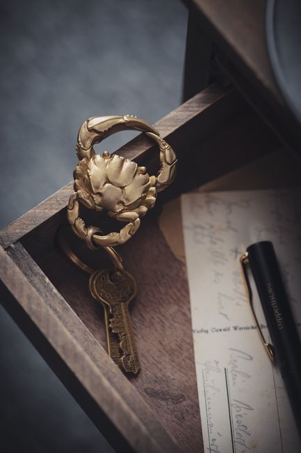 A golden crab keychain with keys inside a wooden drawer, showcasing elegance and craftsmanship.