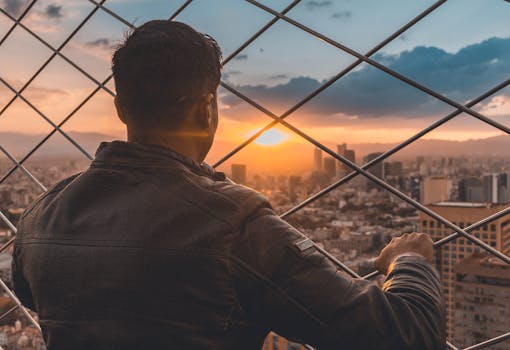 A man gazing at a stunning cityscape view during sunset, creating a dramatic urban atmosphere.