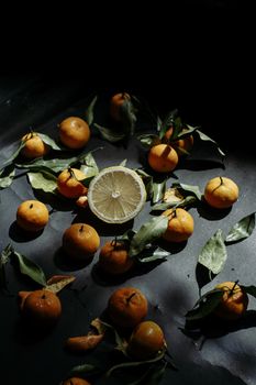 Creative arrangement of tangerines and lemon in dramatic light with fall ambiance.