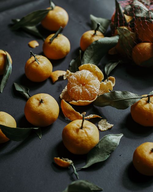 Free Fresh, juicy mandarins with leaves on a dark surface, showcasing vibrant color and abundance. Stock Photo