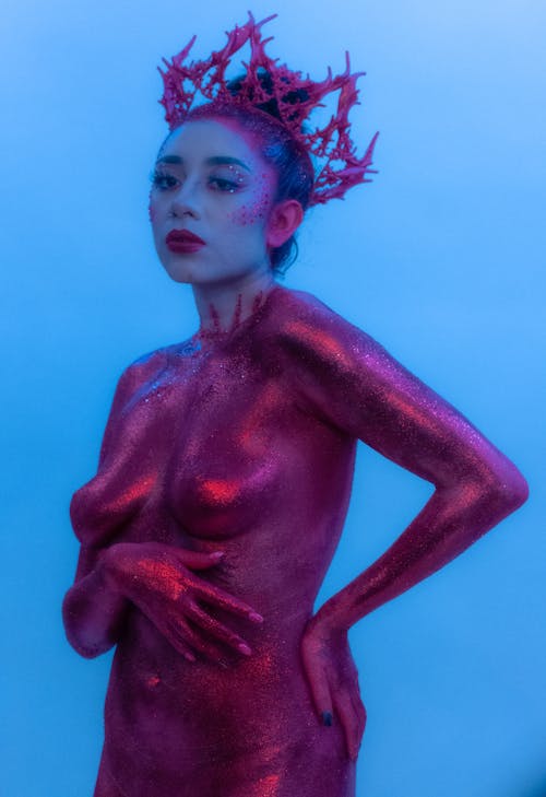 Woman Covered in Pink Glitter Posing on Blue Background 