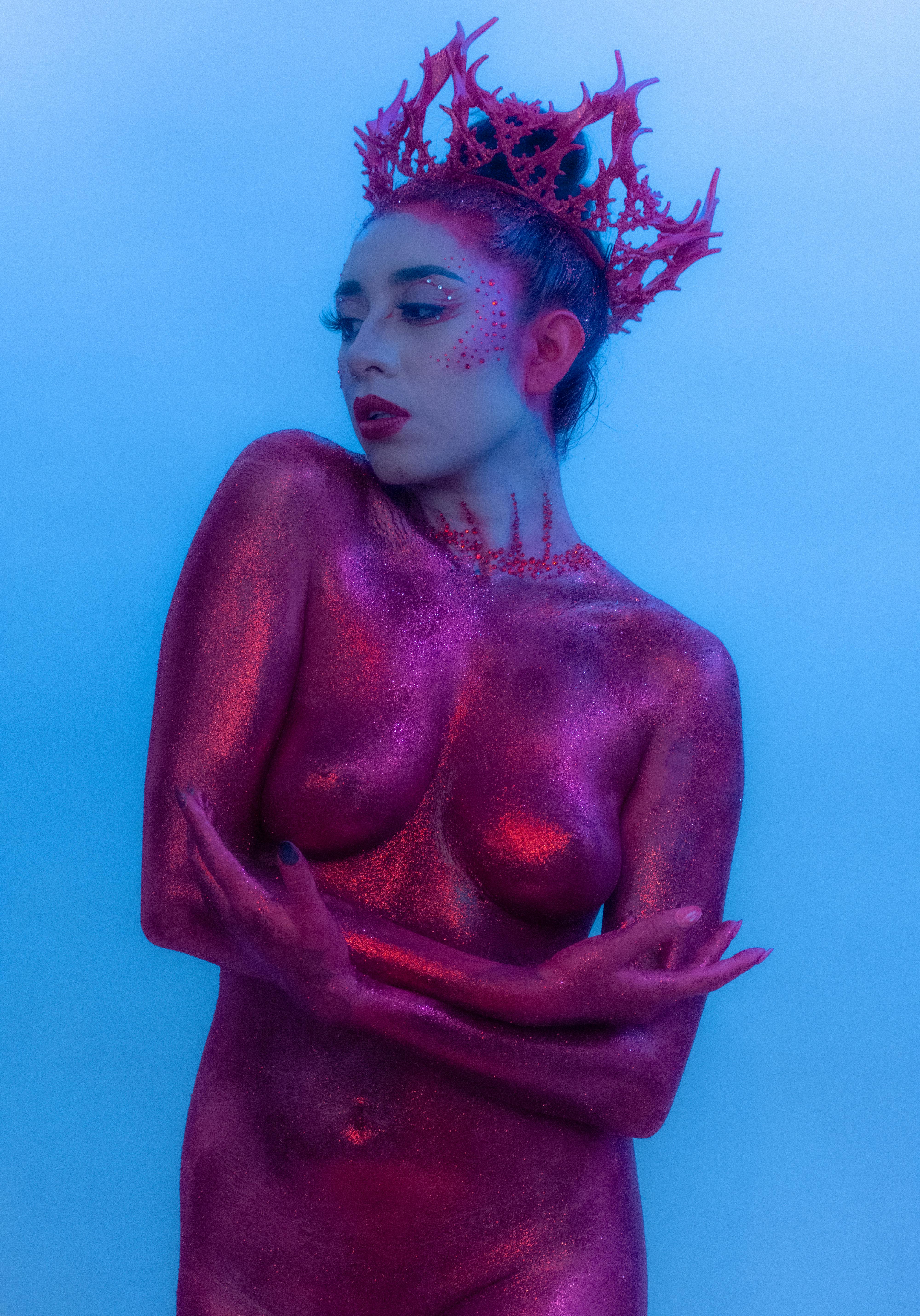 A striking fantasy portrait of a woman covered in pink glitter body paint, wearing a unique crown.