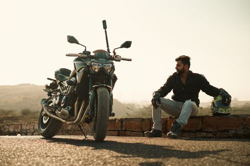 Free Man sitting on brick wall with helmet and motorbike, Jodhpur view. Stock Photo