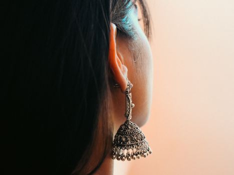Detailed view of a woman's ear adorned with intricate silver earring.