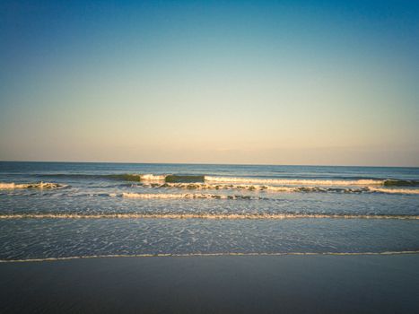 Serene beach waves gently rolling onto the sandy shore during sunset in India.