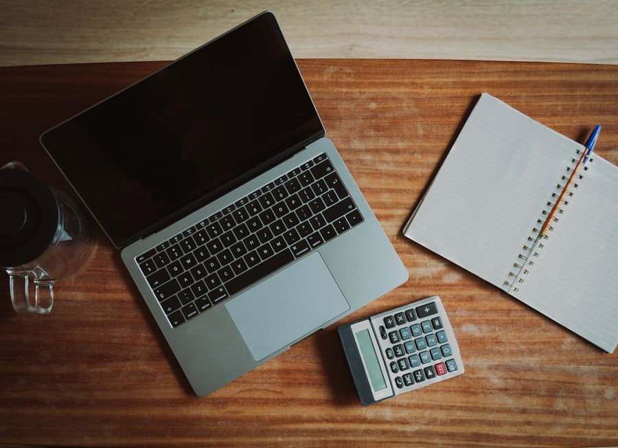 A desk with a laptop, calculator, and notepad for managing finances