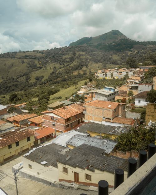 Free Aerial view of a colorful town nestled in a lush valley with mountains in the background. Stock Photo
