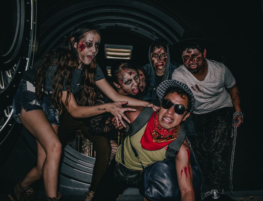 Group of people in zombie makeup, embracing a Halloween theme at night in Ciudad de México.