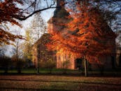 晴朗的天空下，一座历史悠久的教堂被充满活力的秋叶环绕，景色迷人