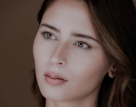 Close-up studio portrait of a young woman with soft lighting and neutral tones.