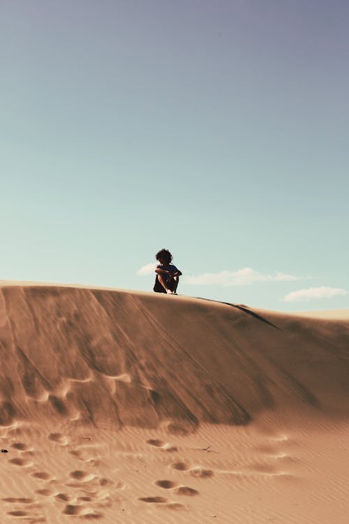 Silhouette of a Person Sitting on a Desert Dune