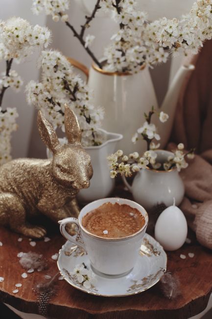 A charming spring scene with coffee, bunny figurine, and blossoming flowers.