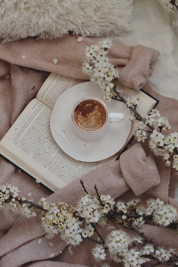 Coffee Cup On Book Near Flowers