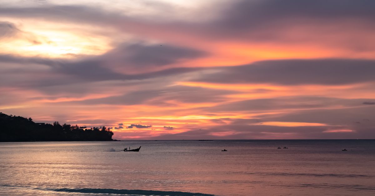Beautiful sunset over the sea in Phuket, Thailand with colorful clouds and calm water.