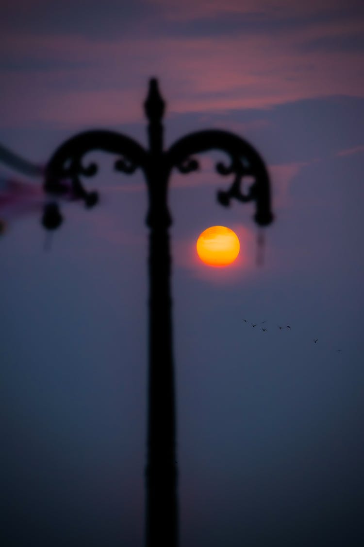 Silhouette Of Street Pillar Behind Sun In Sky