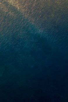 Birds eye view of the vast blue ocean surface captured with a drone, showcasing calm waters.