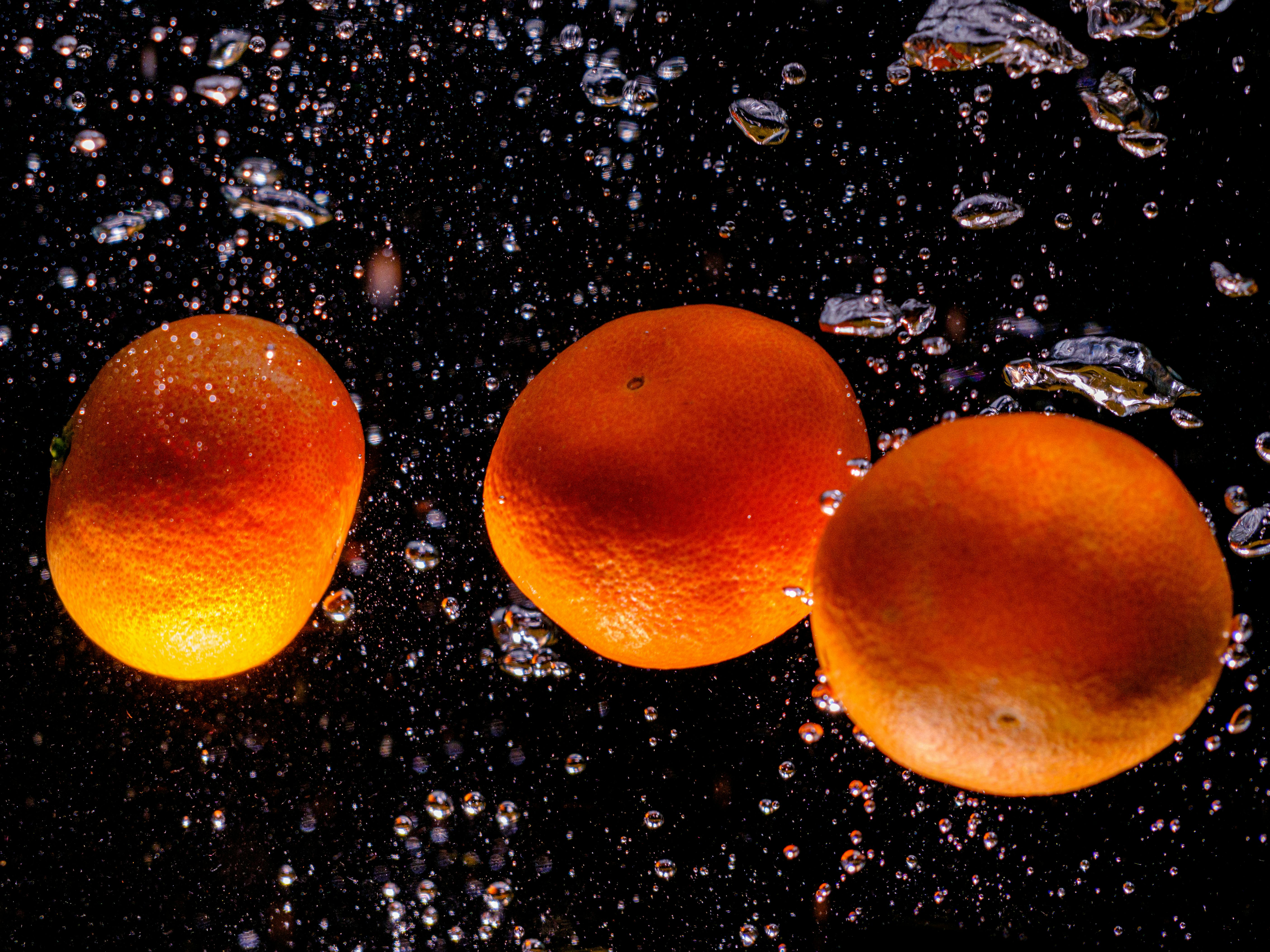 tangerines falling into water with splash on black background