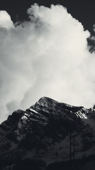 Striking black and white photo of a snowcapped mountain under a cloudy sky, perfect for winter themes.
