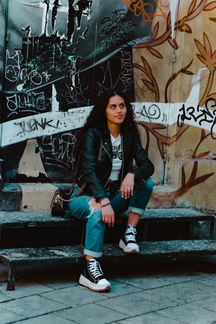 Woman Sitting In Front Of Graffiti