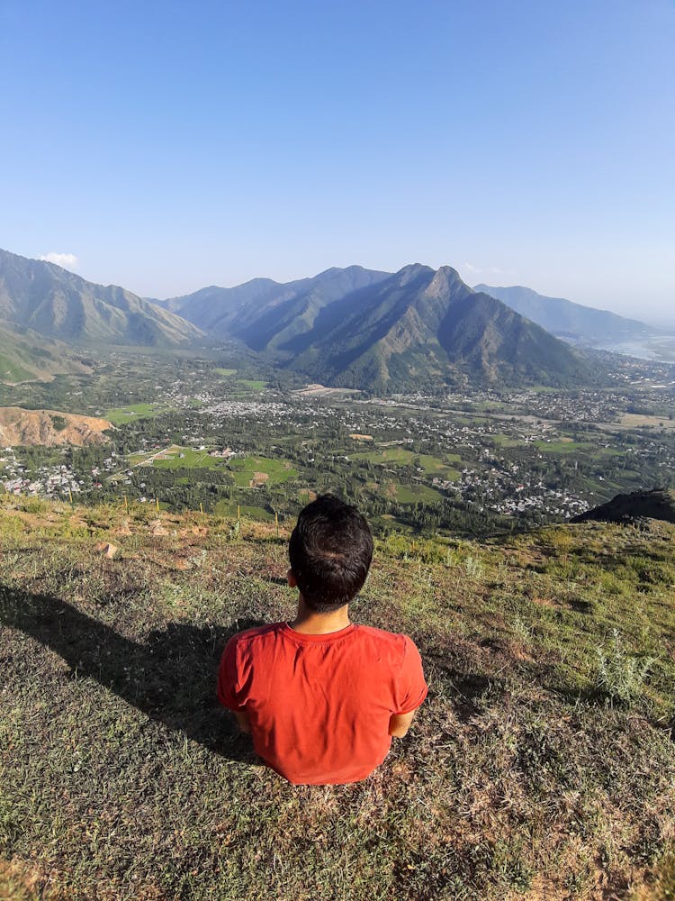 Back View Of Man Sitting On Hilltop