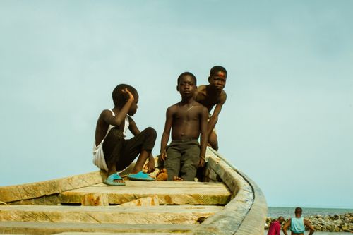 Free Young boys enjoying a summer day sitting on a moored boat by the seaside. Stock Photo