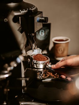 Barista preparing fresh coffee grounds using espresso machine in Baku cafe.