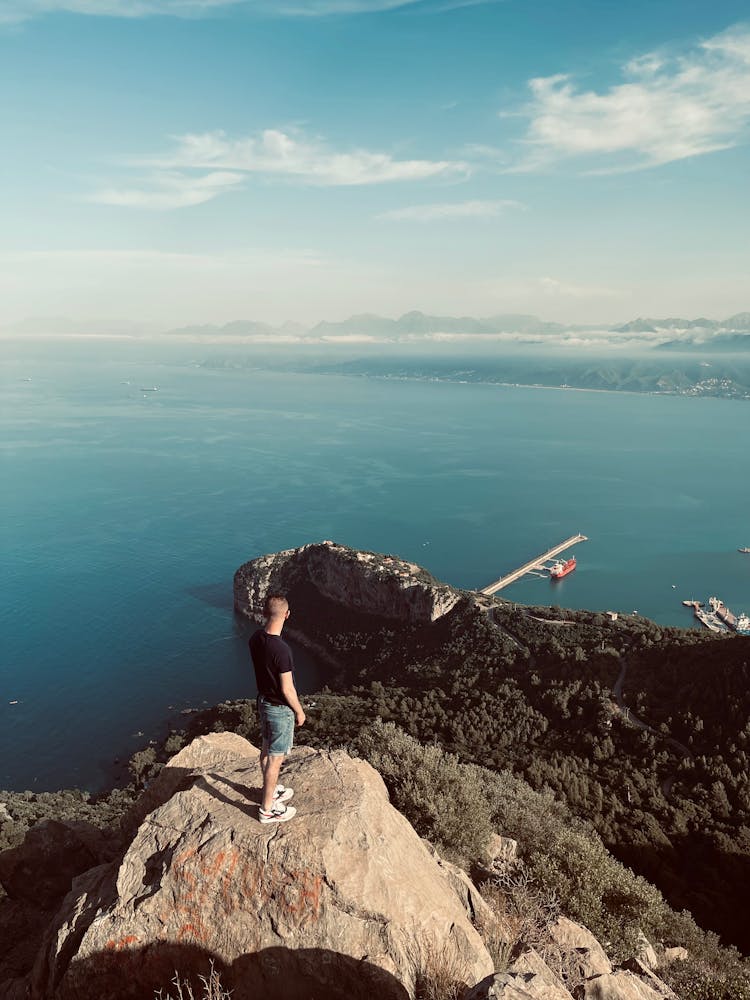 Man Standing On The Top Of The Pic Des Singes Overlooking The Coast In Algeria