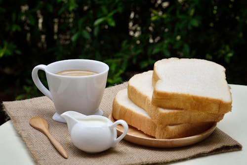 白いセラミックコーヒーカップの横にある3つのスライスしたパン