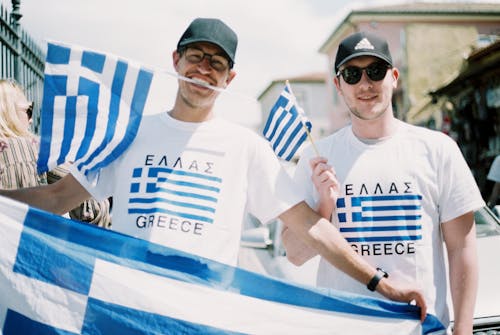 Man Wearing T-shirts and Holding Flags of Greece