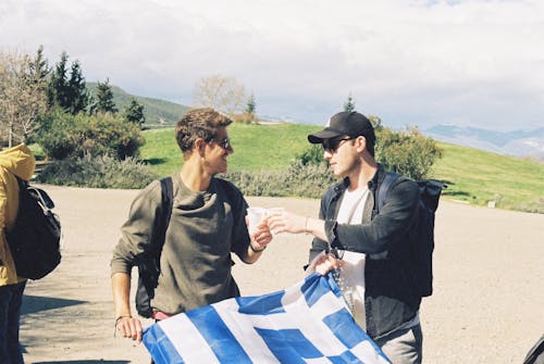 Young Men in Mountains Holding a Greek Flag and Clinking Glasses 