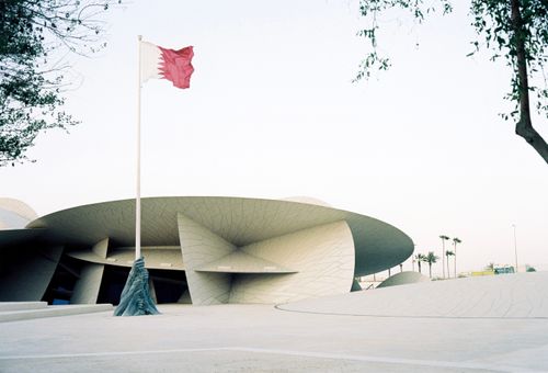 Free Elegant modern architecture of the National Museum of Qatar with waving flag. Stock Photo