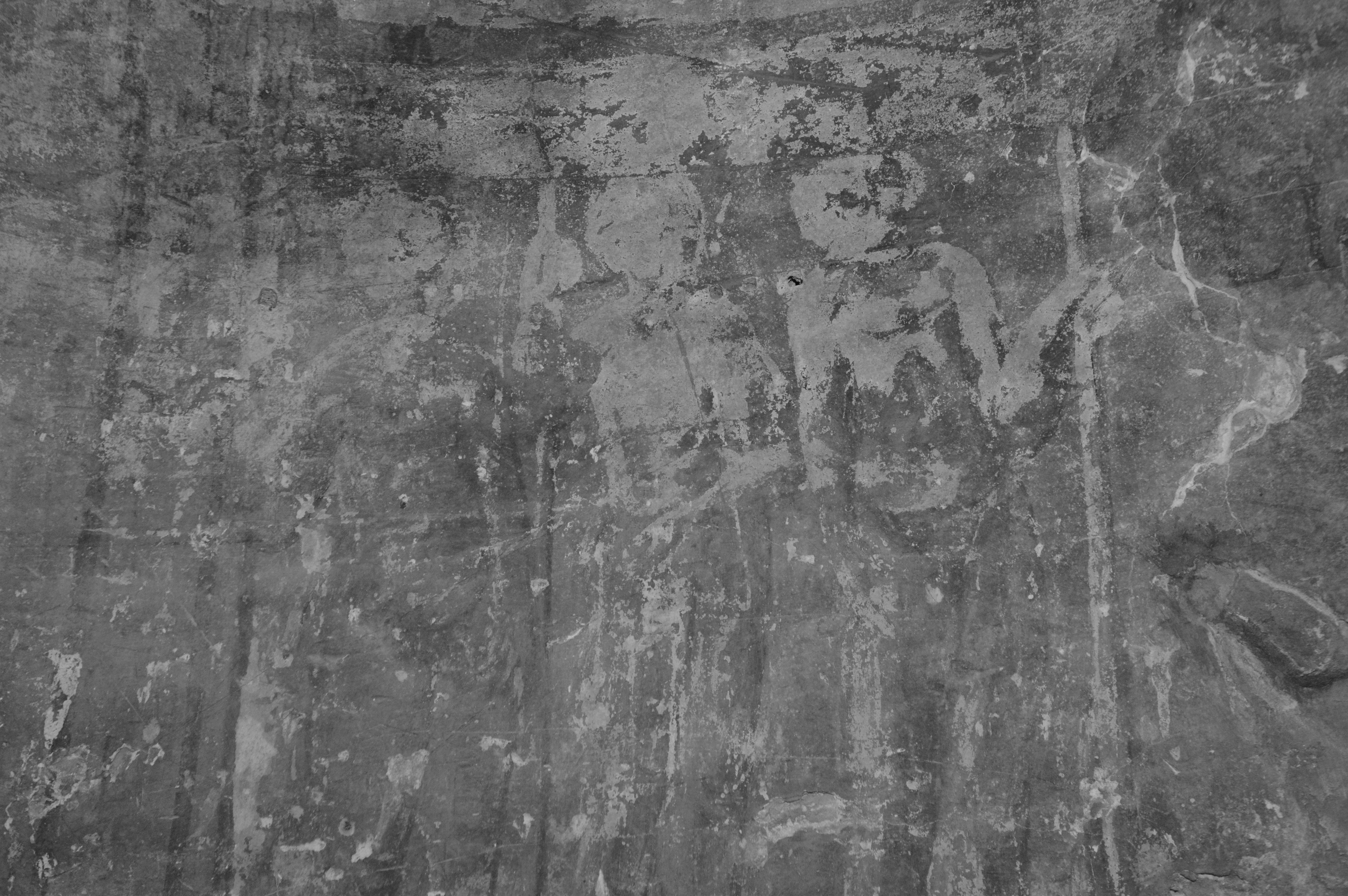 Black and white photo of ancient rock art depicting human figures on a textured surface.