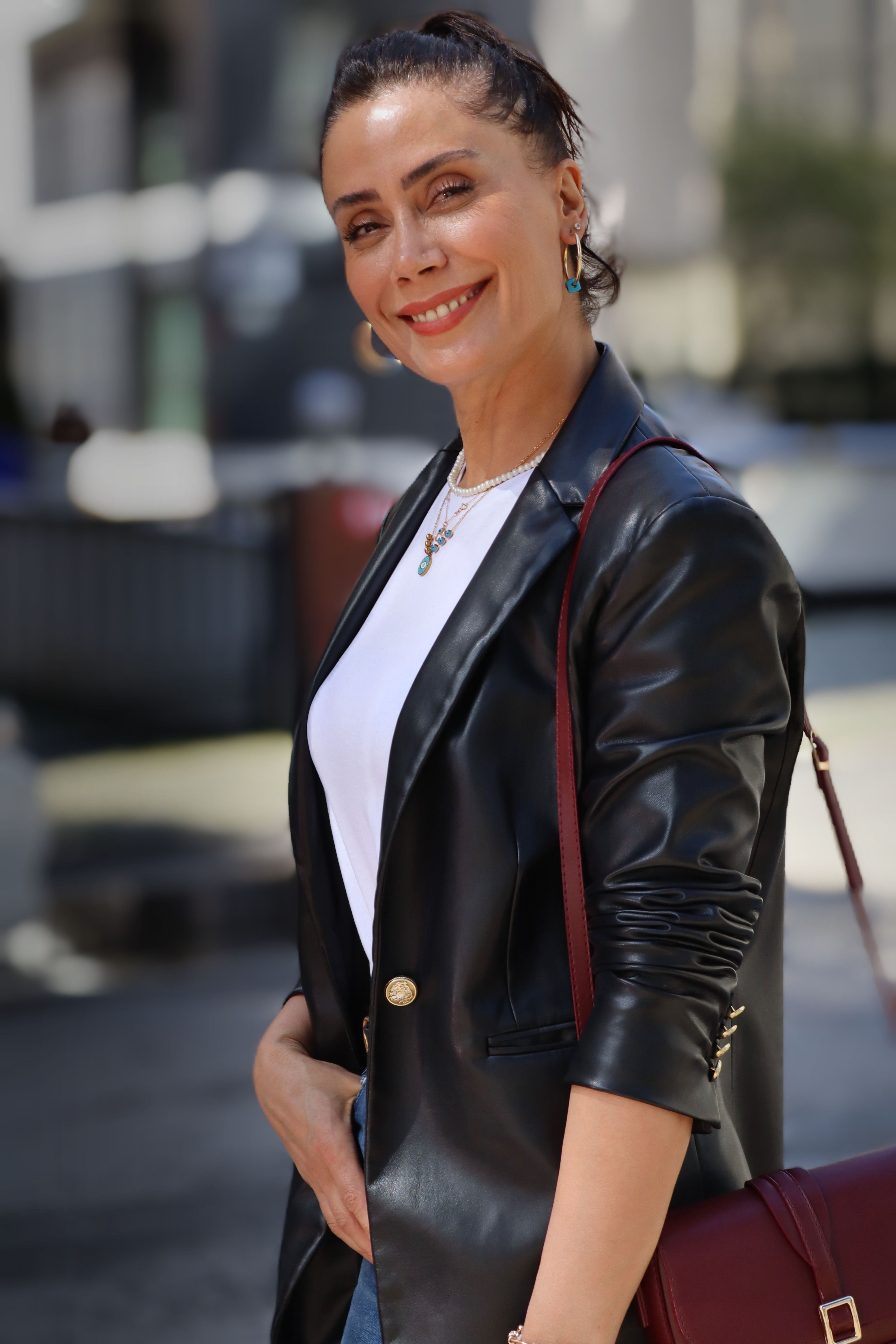 Stylish woman outdoors in leather jacket, exuding confidence and warmth.