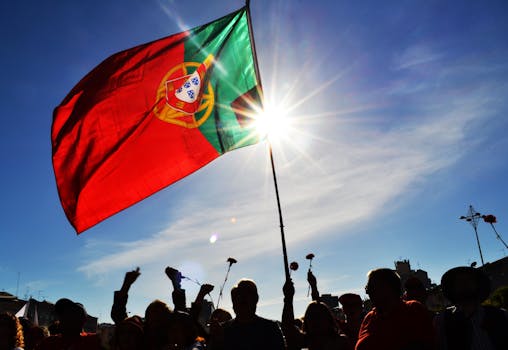 Silhouettes hold flowers and Portuguese flag at sunset in Lisbon, Portugal.
