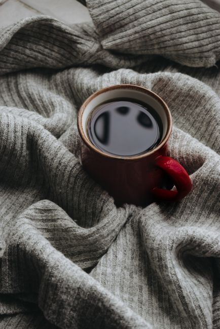 A cozy scene with a coffee mug on a knit blanket, perfect for winter warmth.