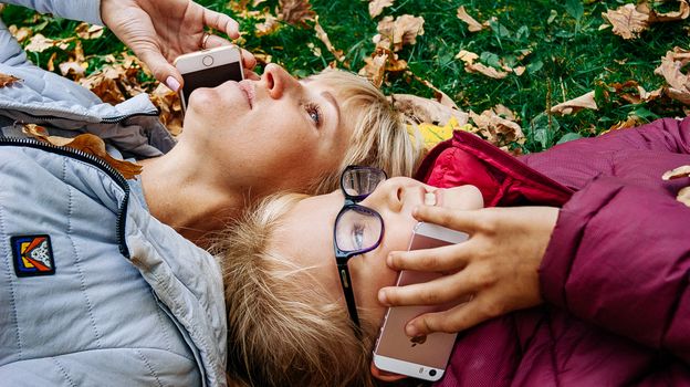 Mother and Son Lying Down with Iphones