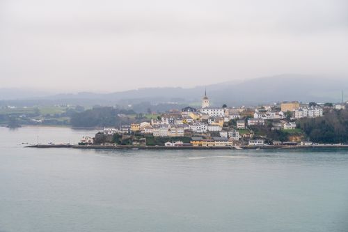 Free Picturesque view of a coastal town with a prominent church steeple on a foggy day. Stock Photo