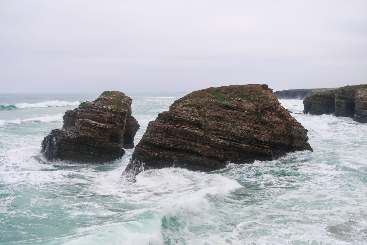 Stânci pe o plajă sub cer înnorat, pe coasta Galiției