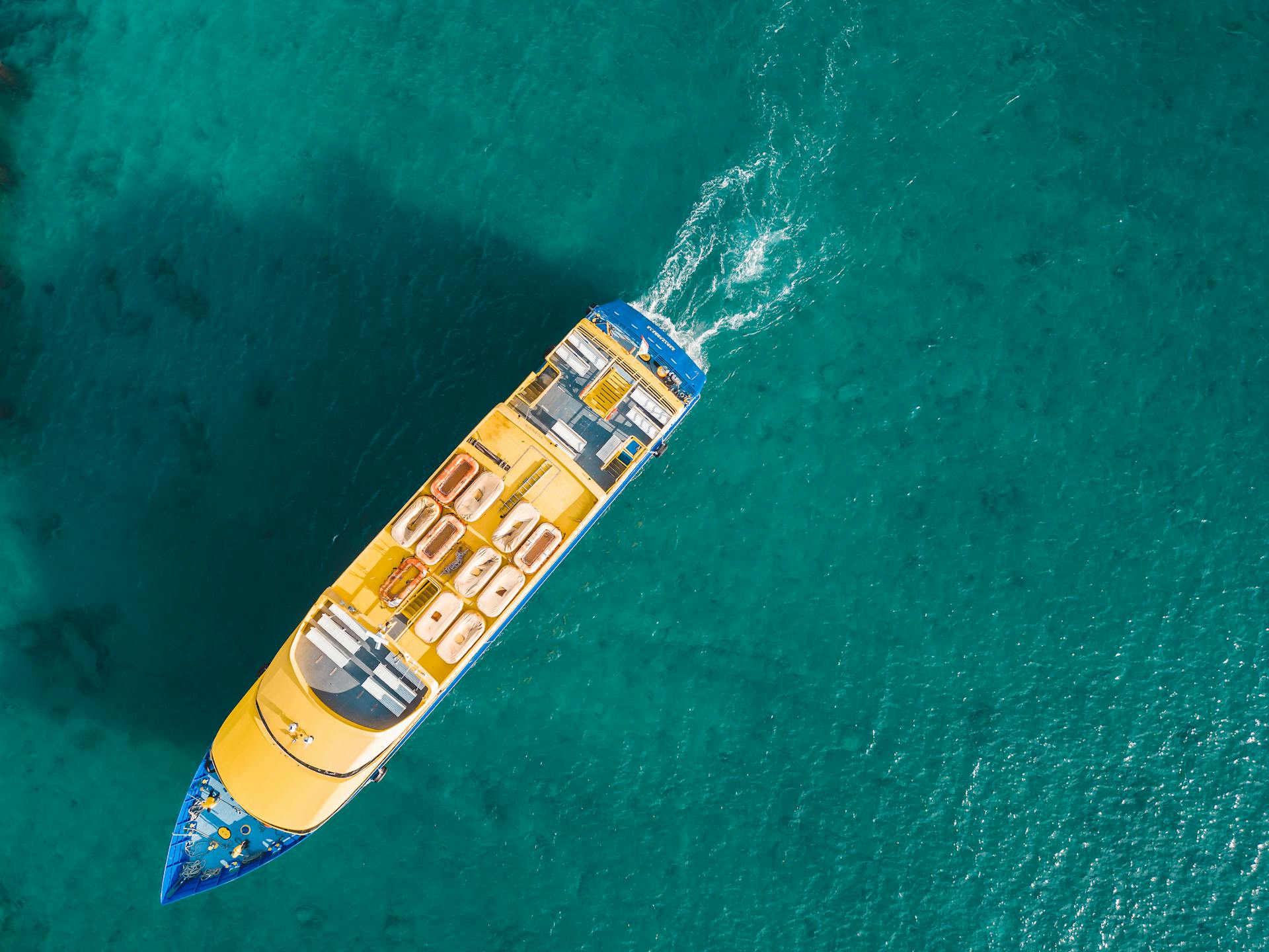 Aerial view of a vibrant yacht sailing in clear turquoise waters near Playa del Carmen, Mexico.