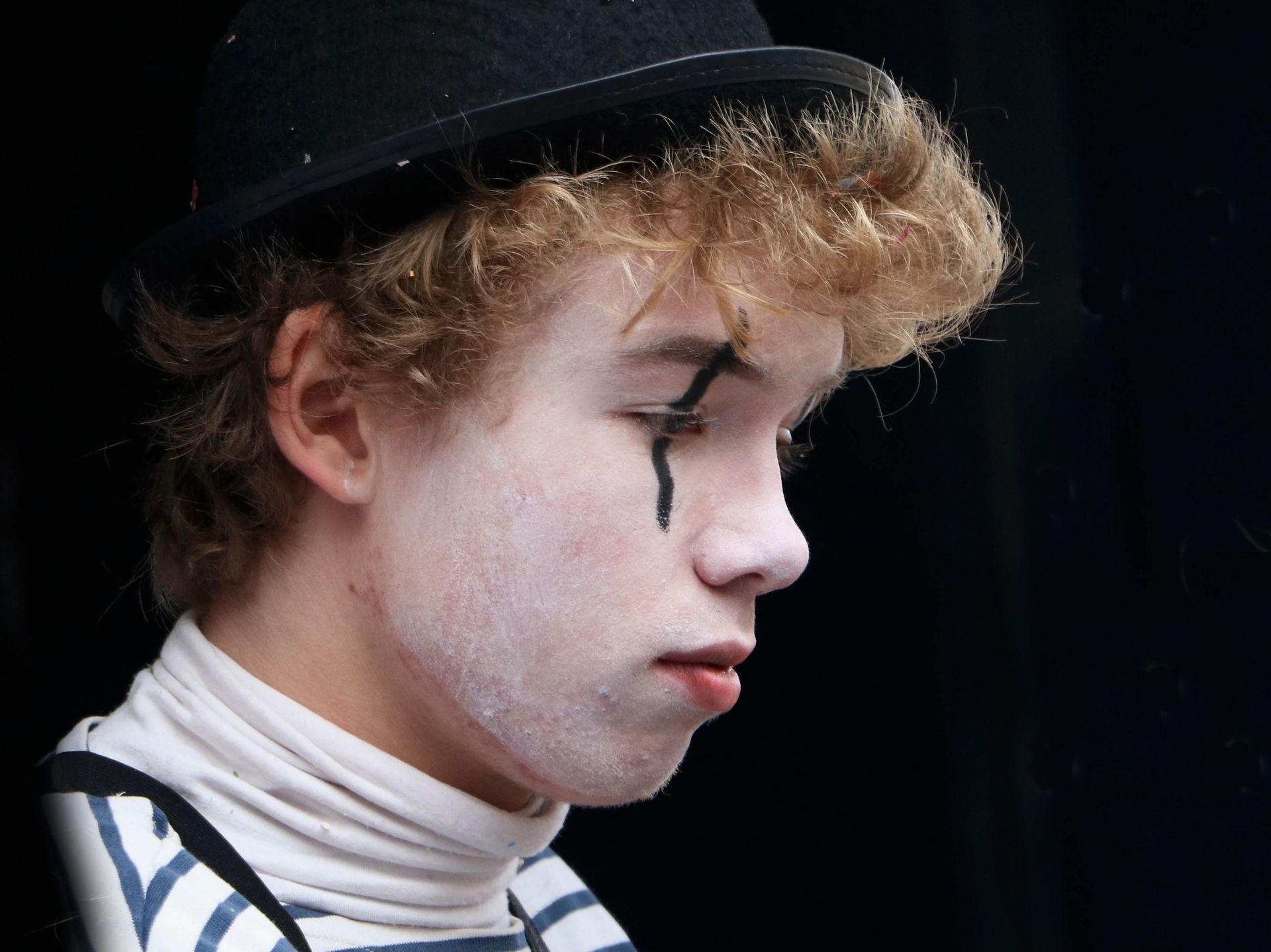 Close-up of a mime performer wearing makeup and a hat in Granville