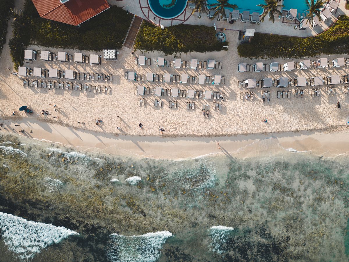 Aerial shot of a beachfront resort in Playa del Carmen, showing sun loungers, be