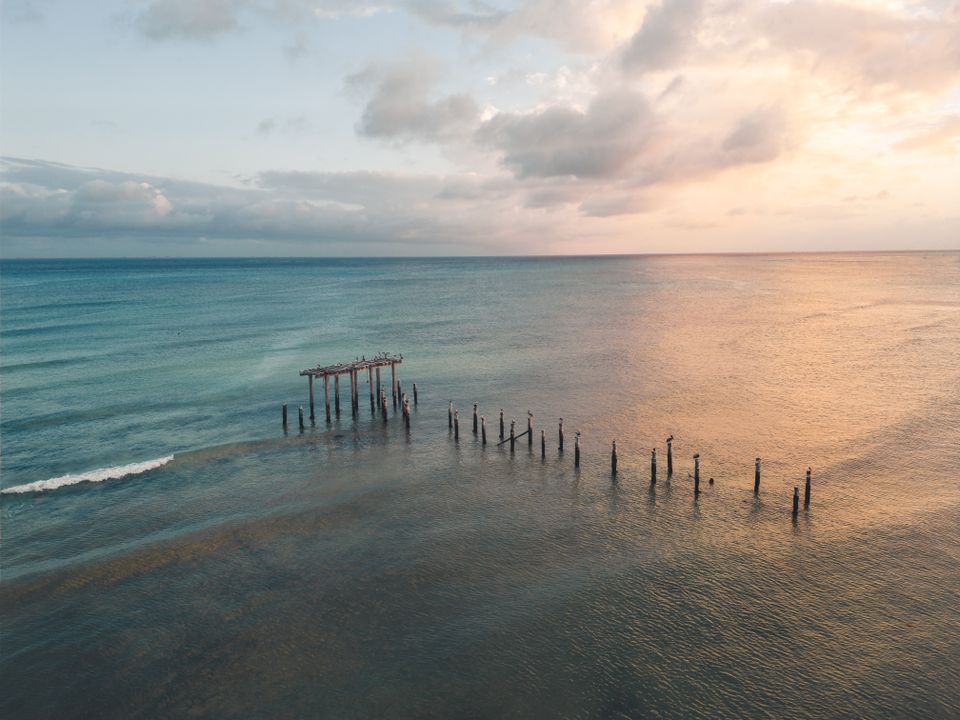 Restos de un antiguo muelle se asoman sobre el agua al atardecer