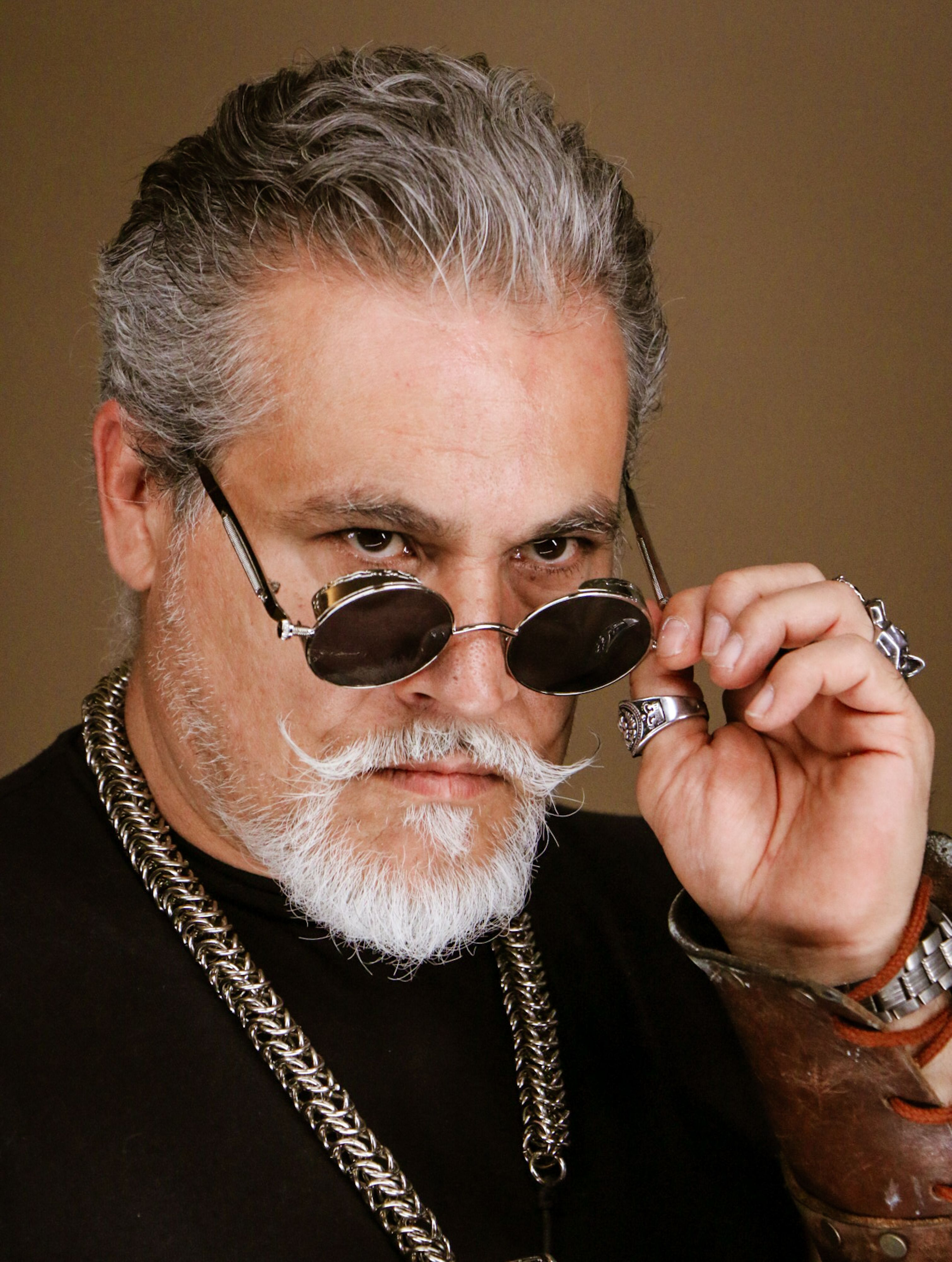 Portrait of a mature man with silver beard adjusting sunglasses, showcasing style and confidence.
