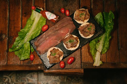 Delicious meat platter with greens and spicy Tabasco for a perfect meal.