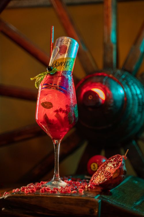 Free A vibrant cocktail with pomegranate seeds and a mint garnish, set against a warm, artistic background. Stock Photo