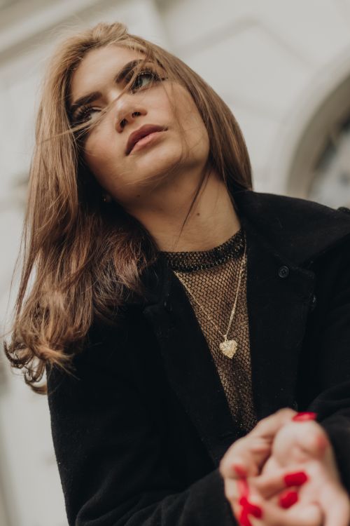 Free Stylish woman with brown hair posing outdoors in a fashionable black ensemble, showcasing elegance and confidence. Stock Photo